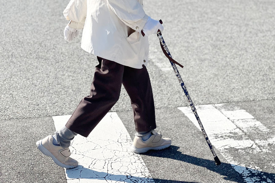 レンタルした歩行補助つえを使って歩く女性